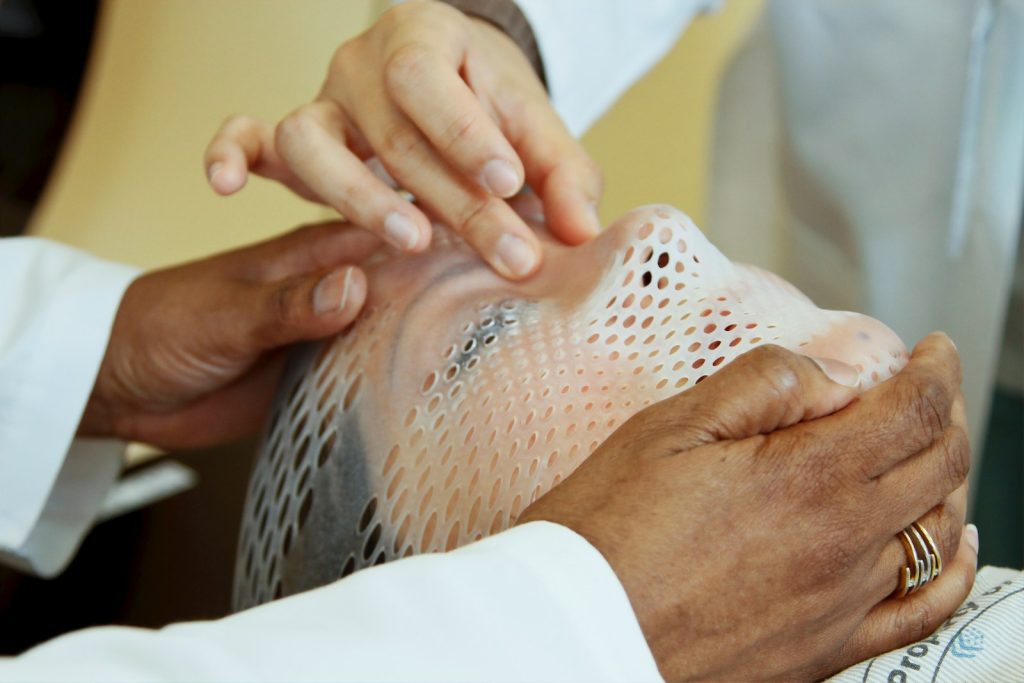 person holding man's face receiving oncology treatment for cancer patient care