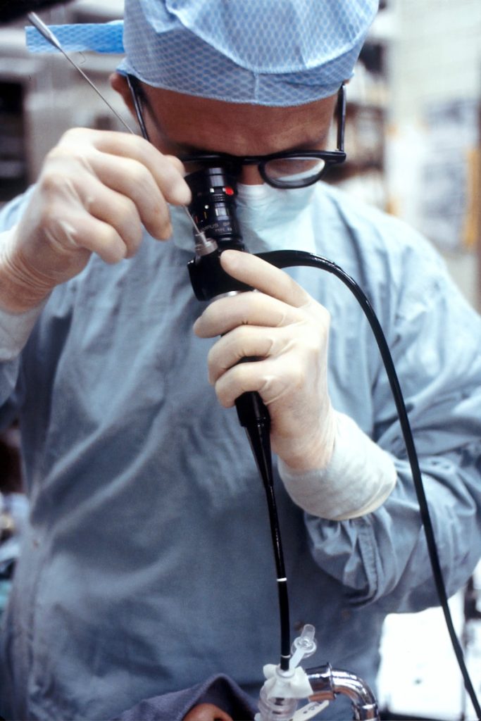 man in blue dress shirt holding black corded device 