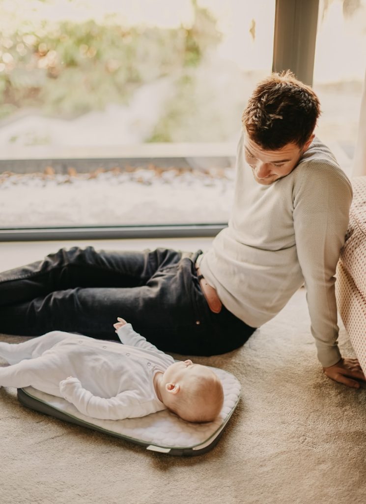 man in gray sweater lying on floor beside man in black shirt